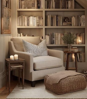 Cozy reading nook with beige armchair, bookshelves, candles, and woven pouf in warm neutral tones
