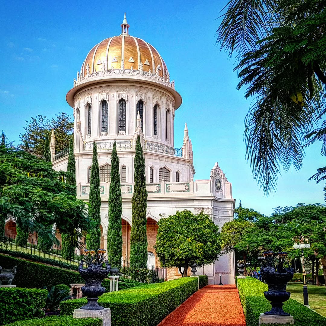 Bahá'í temple with golden dome surrounded by manicured gardens and palm trees in Haifa