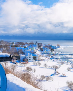 Snowy village with white church and buildings overlooking frozen waterfront in winter