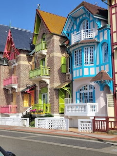 Row of colorful Victorian-style houses with bright green, yellow, pink, and blue facades on a street