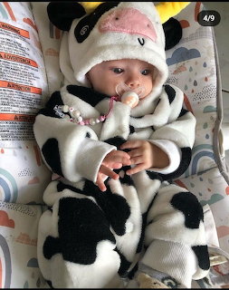 Baby in black and white panda costume lying down with pacifier