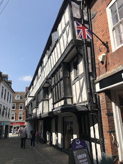 Narrow street in Shrewsbury with black and white timber-framed Tudor buildings Union Jack flag
