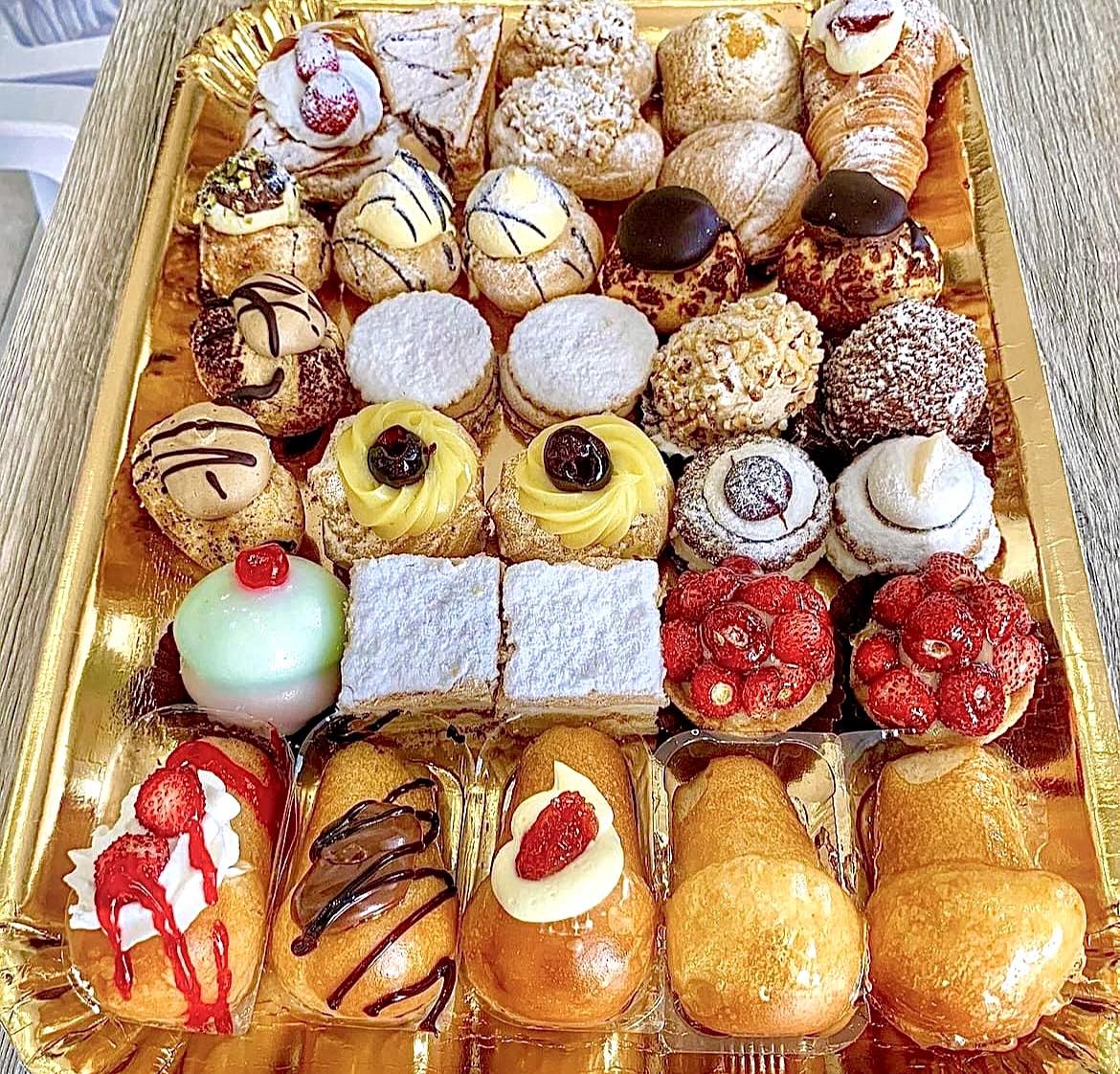 Gold tray of assorted Italian pastries and desserts arranged in rows