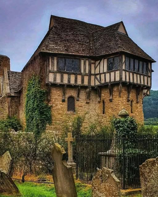 Historic timber-framed castle gatehouse with half-timbered upper floor and stone base surrounded by green lawn