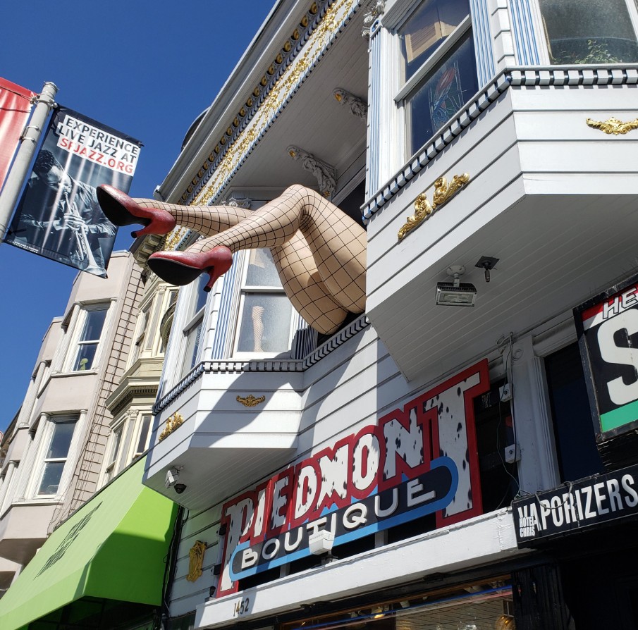 Building facade with giant mannequin legs protruding above the Piedmont Boutique storefront sign