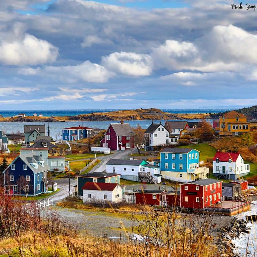 Colorful houses in a coastal village beneath a cloudy sky by the water