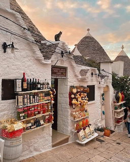 Whitewashed trulli buildings with cone rofs and a souvenir shop in Alberobello, Italy at sunset