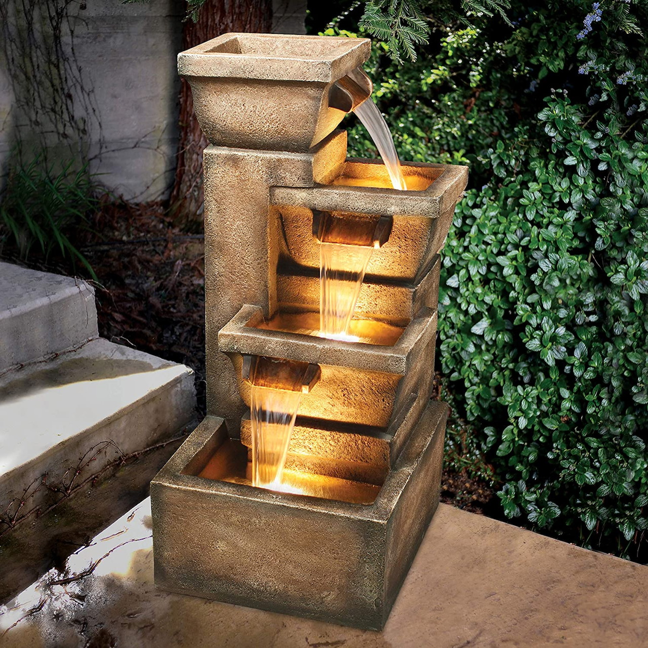 Tiered stone water fountain with glowing basins in garden