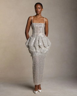 Woman in silver sequin peplum midi dress with spaghetti straps posing against beige background
