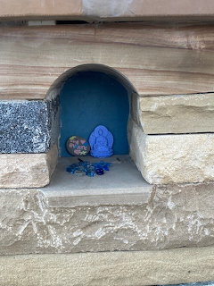 Small blue grotto niche in stone wall with decorative figurines