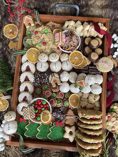 Wooden tray filled with colorful decorated Christmas cookies including gingerbread men, snowmen, and festive sugar cookies