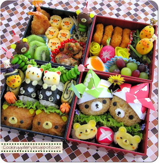 Cute bento lunch box with animal-shaped rice balls, colorful vegetables, and fruit arranged in four compartments