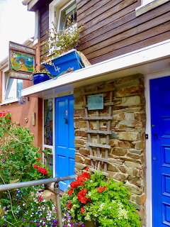 Stone cottage with blue doors and flower boxes in Cawsand village, Cornwall