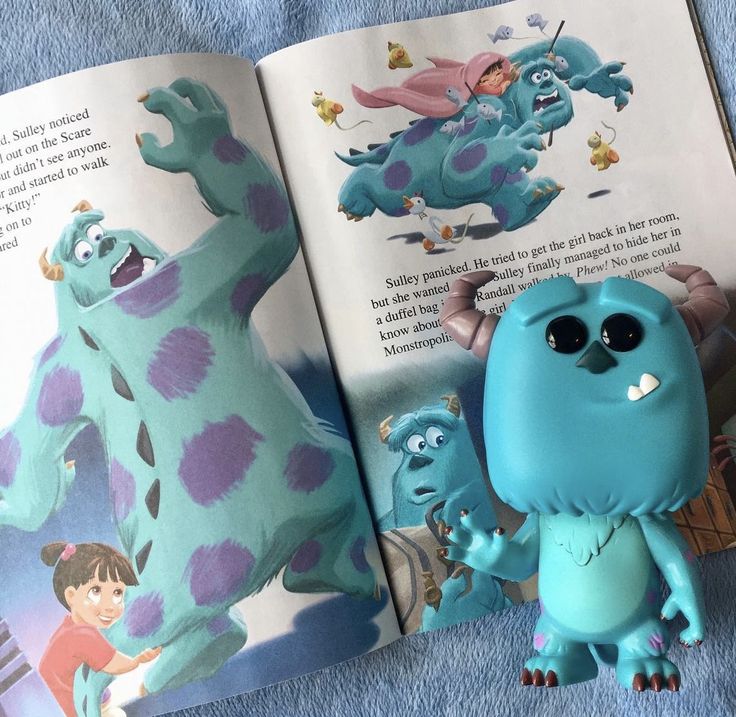 Blue Sulley monster figure on an open illustrated book with Monsters, Inc. character art