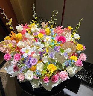 Large colorful flower bouquet with roses, carnations and mixed blooms in a round vase on black surface