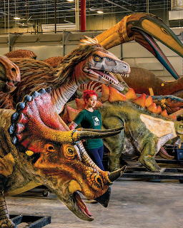 Woman sculptor working on large detailed dinosaur sculpture in art studio