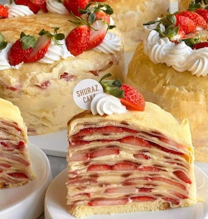 Slices of layered strawberry crepe cake topped with whipped cream and fresh strawberries