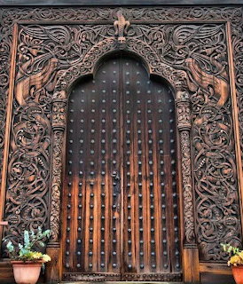 Elaborately carved dark wooden door with Viking-style scrollwork and metal studs in Stockholm