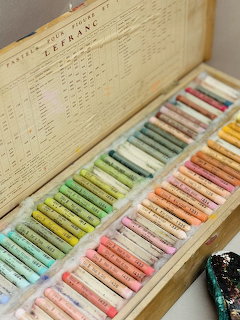 Wooden box of soft pastel sticks arranged in rainbow gradient with color chart in lid