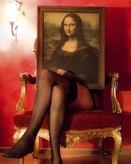 Mona Lisa painting combined with woman's legs in black stockings on ornate gold chair in red room