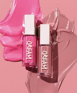 Two lip gloss tubes with white caps on pink background with cream product swatches