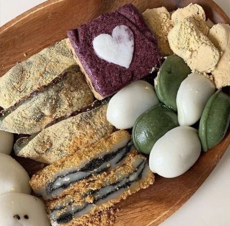 Assorted Korean rice cakes and mochi on a wooden tray