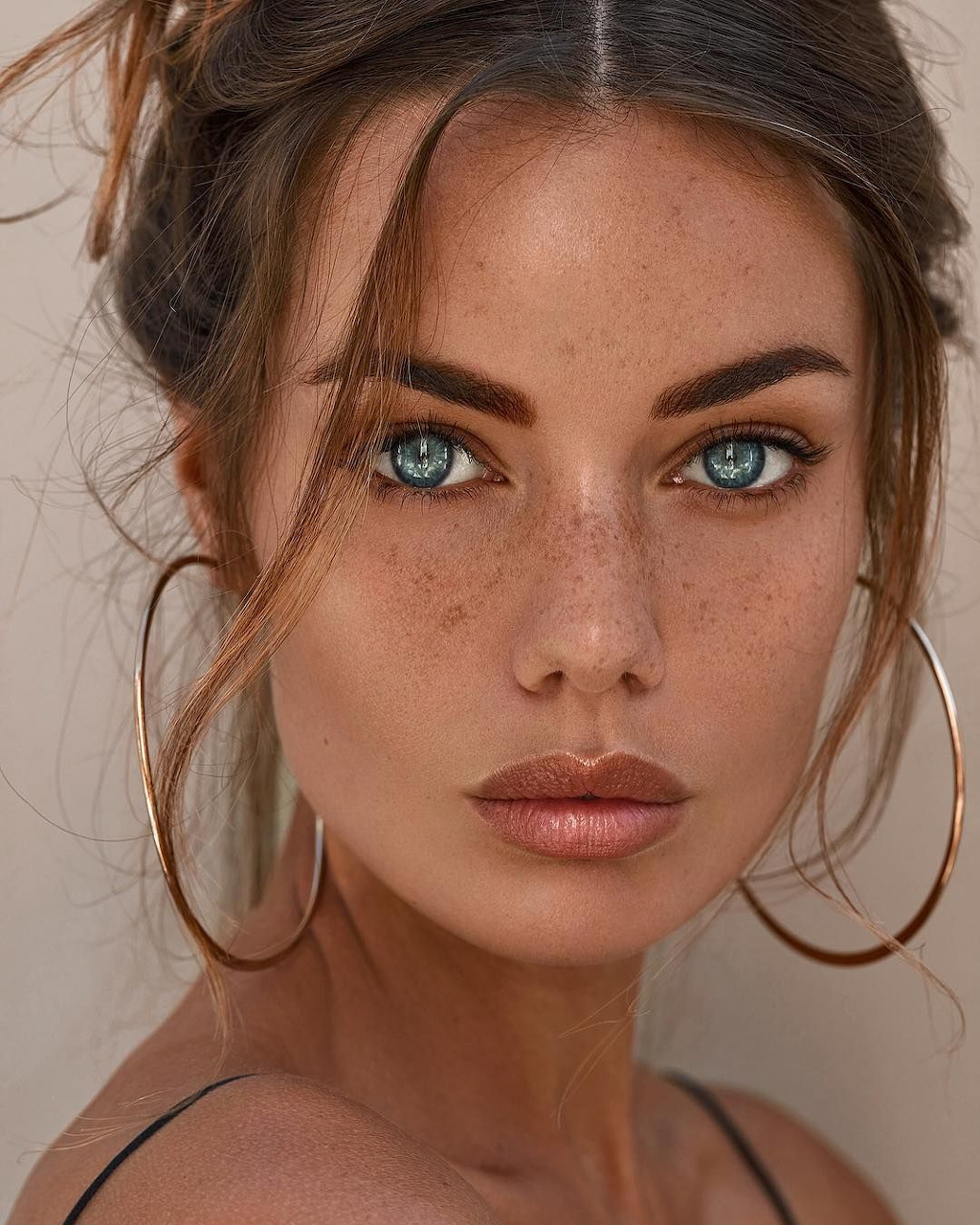 Portrait of woman with blue eyes and hoop earrings looking at camera
