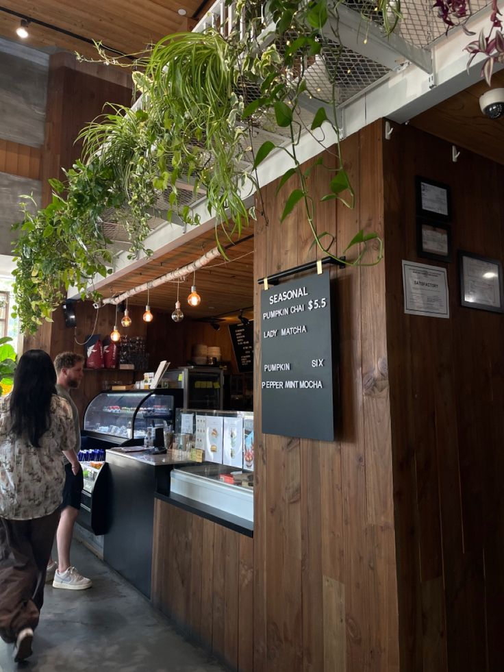 Coffee shop interior with wood counter, hanging plants, and chalkboard menu