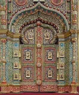 Ornate monastery door with decorative tiles, religious icons, and elaborate carved archway
