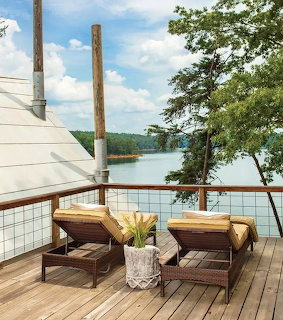 Wooden deck with lounge chairs overlooking calm lake surrounded by trees
