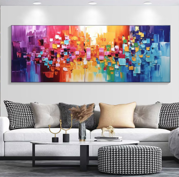 Colorful abstract mosaic painting with geometric blocks in rainbow gradient on white wall above gray sofa