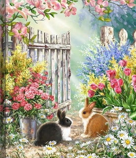 Two rabbits sitting beside a white wooden gate in a blooming garden with pink and blue flowers