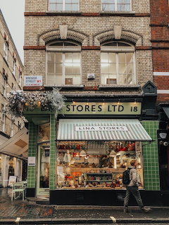 Green Italian delicatessen storefront with striped awning and brick building above in London