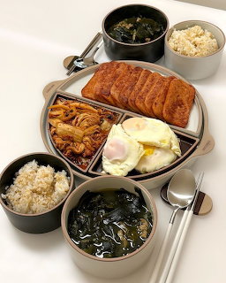 Korean meal tray with sliced meat, rice, seaweed soup, kimchi, and fried eggs