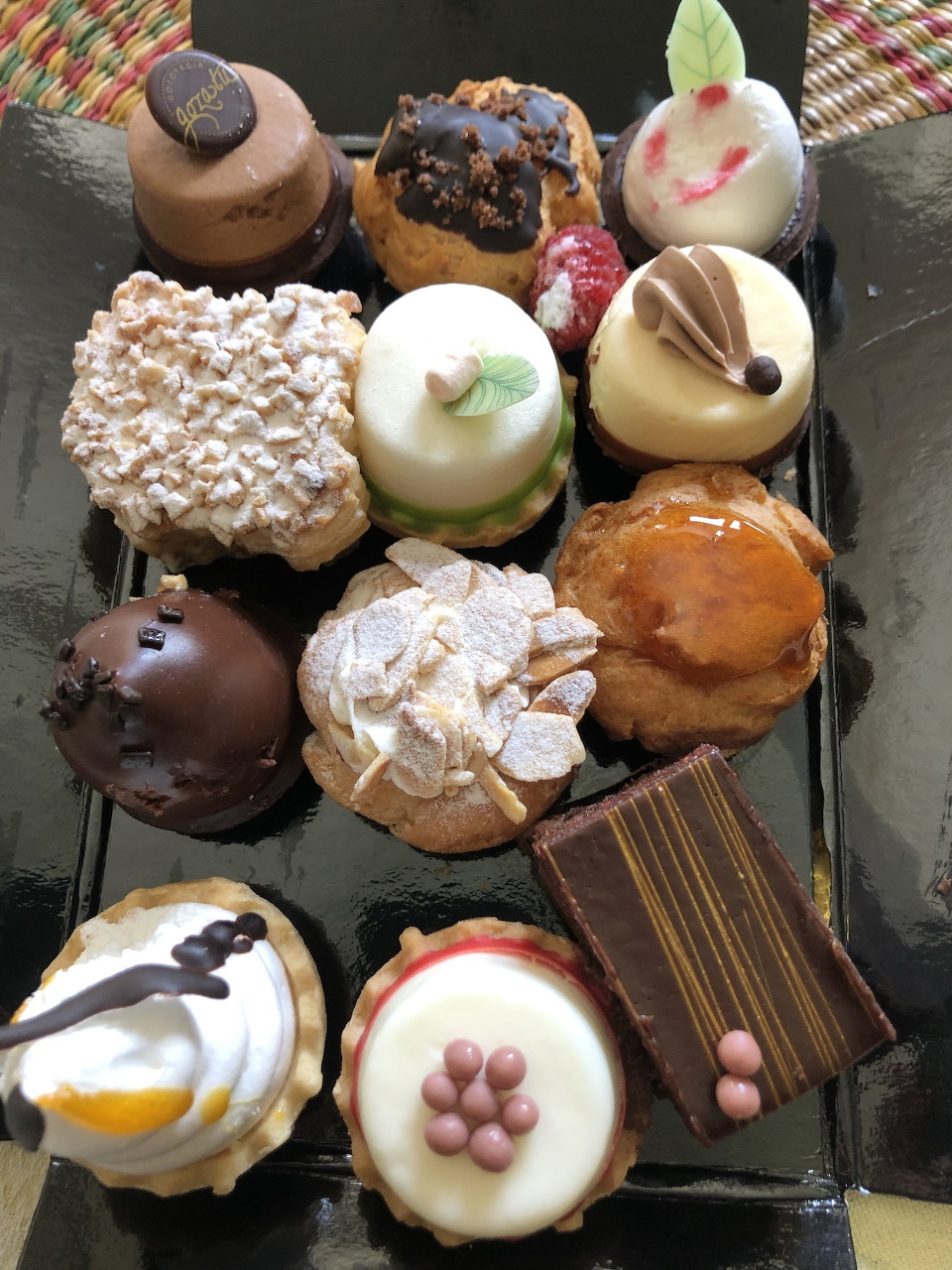 Assortment of colorful French pastries and petit fours on a black tray