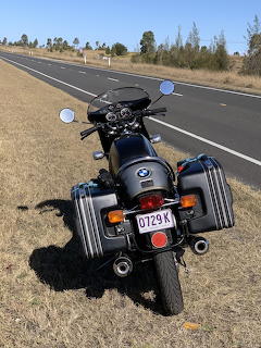 Black BMW motorcycle with saddlebags parked on roadside of a rural Australian highway