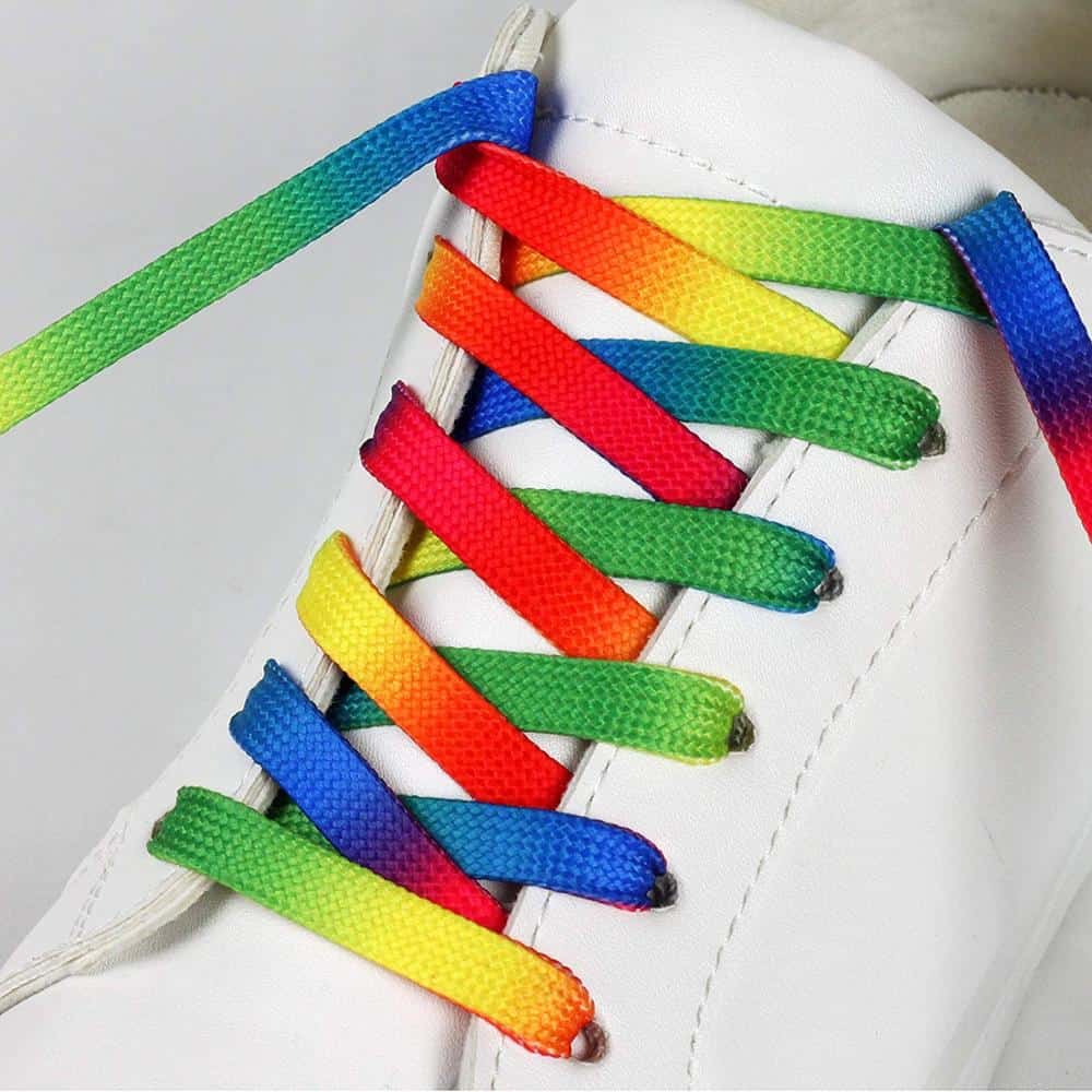 White sneaker with rainbow striped shoelaces in red, yellow, green, and blue