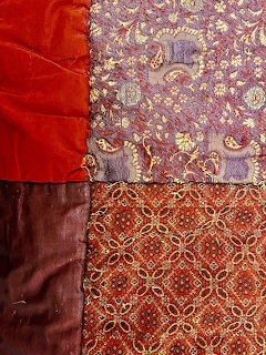 Four fabric squares with burgundy, red and purple patterns including paisley, florals and geometric designs