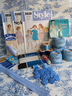 Vintage sewing patterns with blue thread, yarn, buttons, and craft supplies on floral background