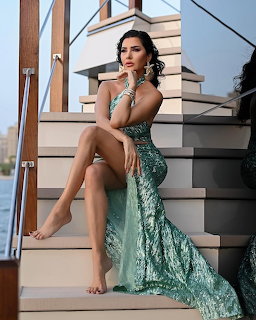 Woman in green sequined dress sitting on white stairs posing elegantly