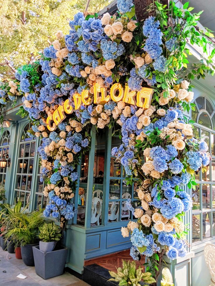 Cafe entrance covered in blue hydrangeas and cream roses forming a lush floral arch