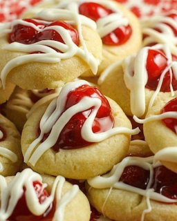 Close-up of cherry thumbprint cookies with white icing drizzle piled together