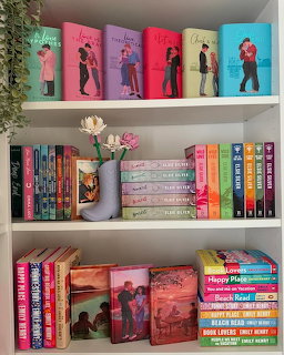 White bookshelf with colorful books, framed photos, and a vase of flowers