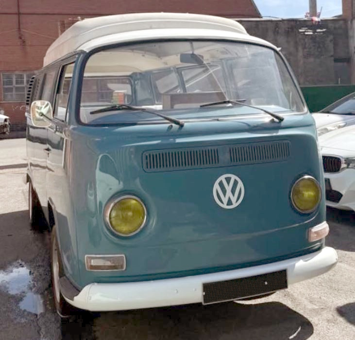 Front view of a vintage blue and white VW camper van parked outdoors