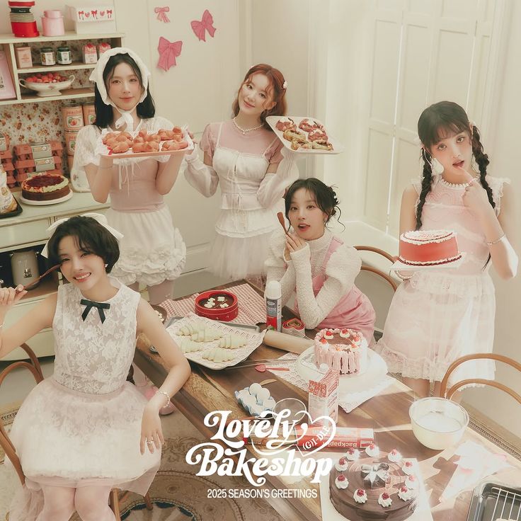 Five women in white dresses holding and displaying pink pastries and cakes in a bakery kitchen