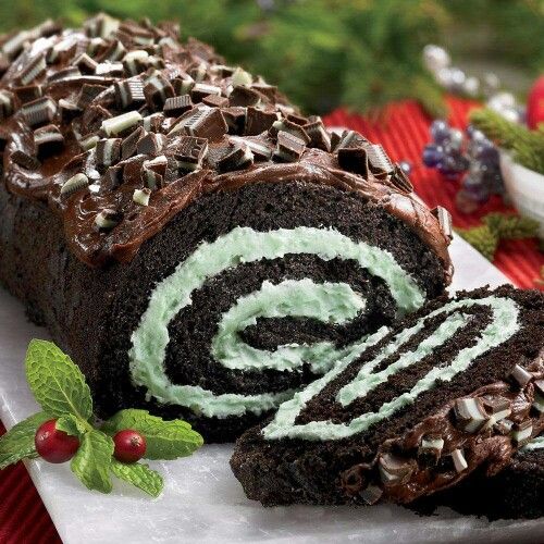Chocolate Swiss roll cake with mint cream filling, chocolate shavings, mint leaves, and red berries