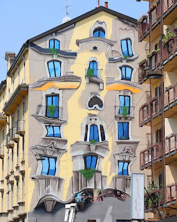 Street art mural on building facade with painted blue windows and architectural trompe-l'oeil details