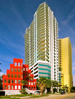 High-rise buildings in Brickell with a red building, palm trees, and blue sky
