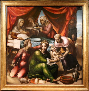 Renaissance painting showing nativity scene with women attending newborn child under red curtain