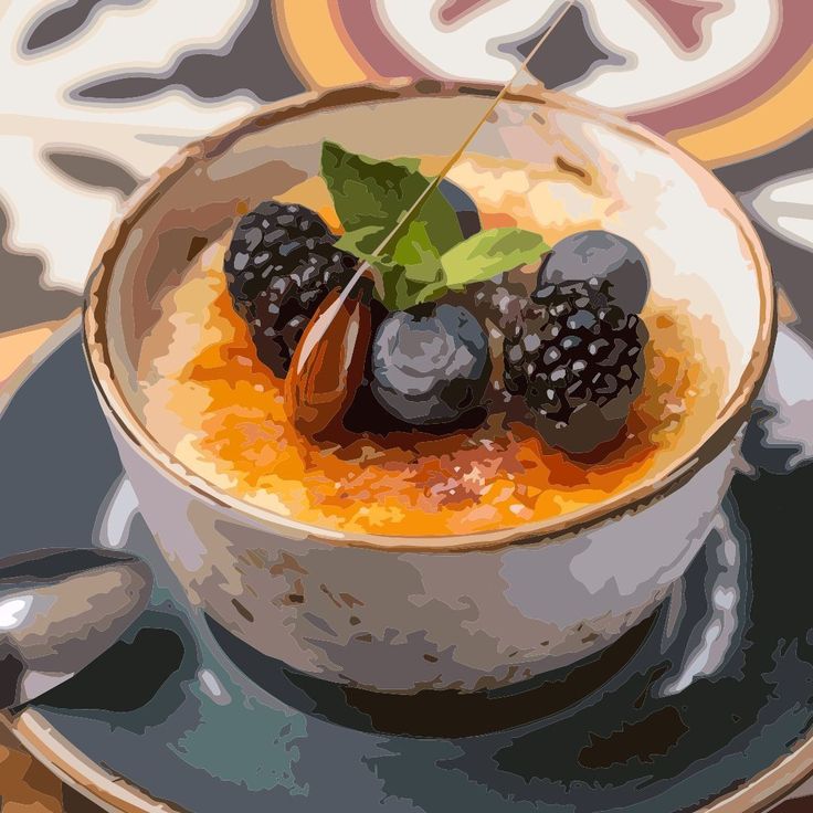 Crème brûlée topped with blackberries, blueberries, and mint in white ramekin